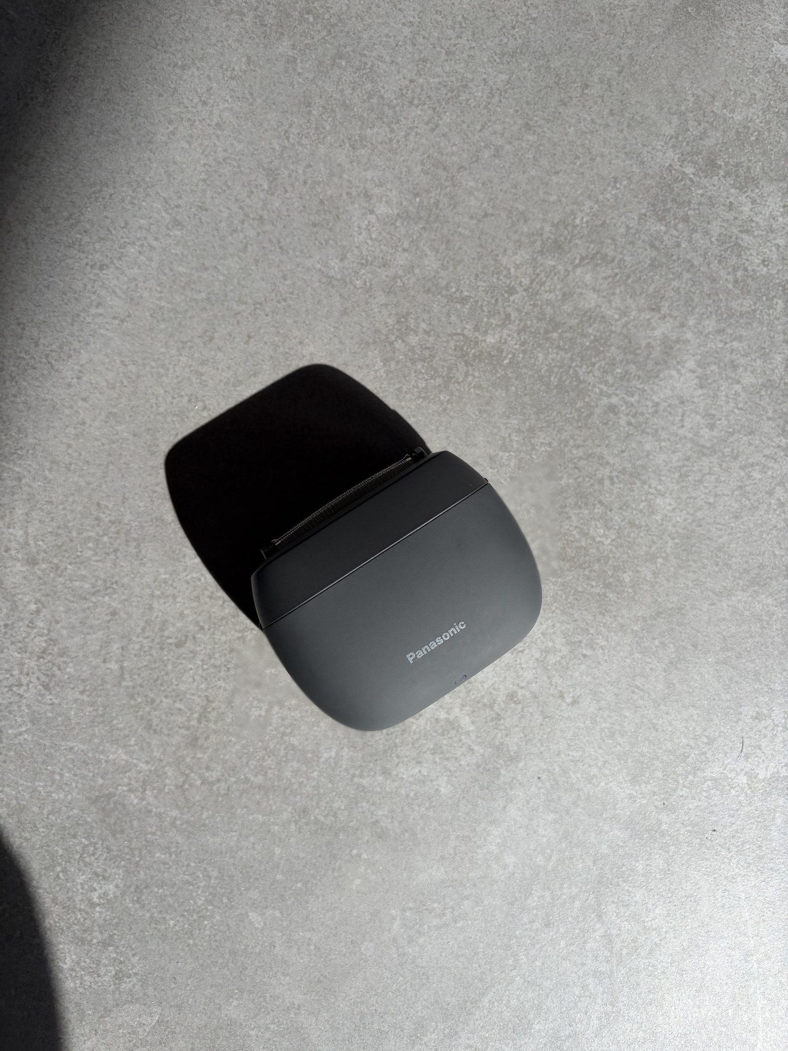 Panasonic ES-PV3B compact electric shaver on grey concrete in hard afternoon light
