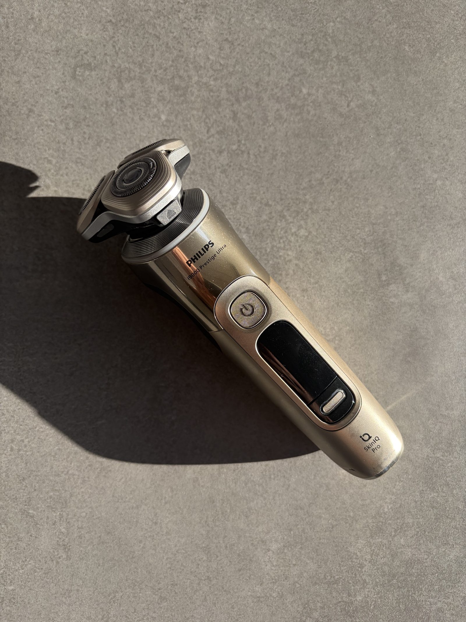 Philips i9000 Prestige Ultra shaver on a stone bench in hard light
