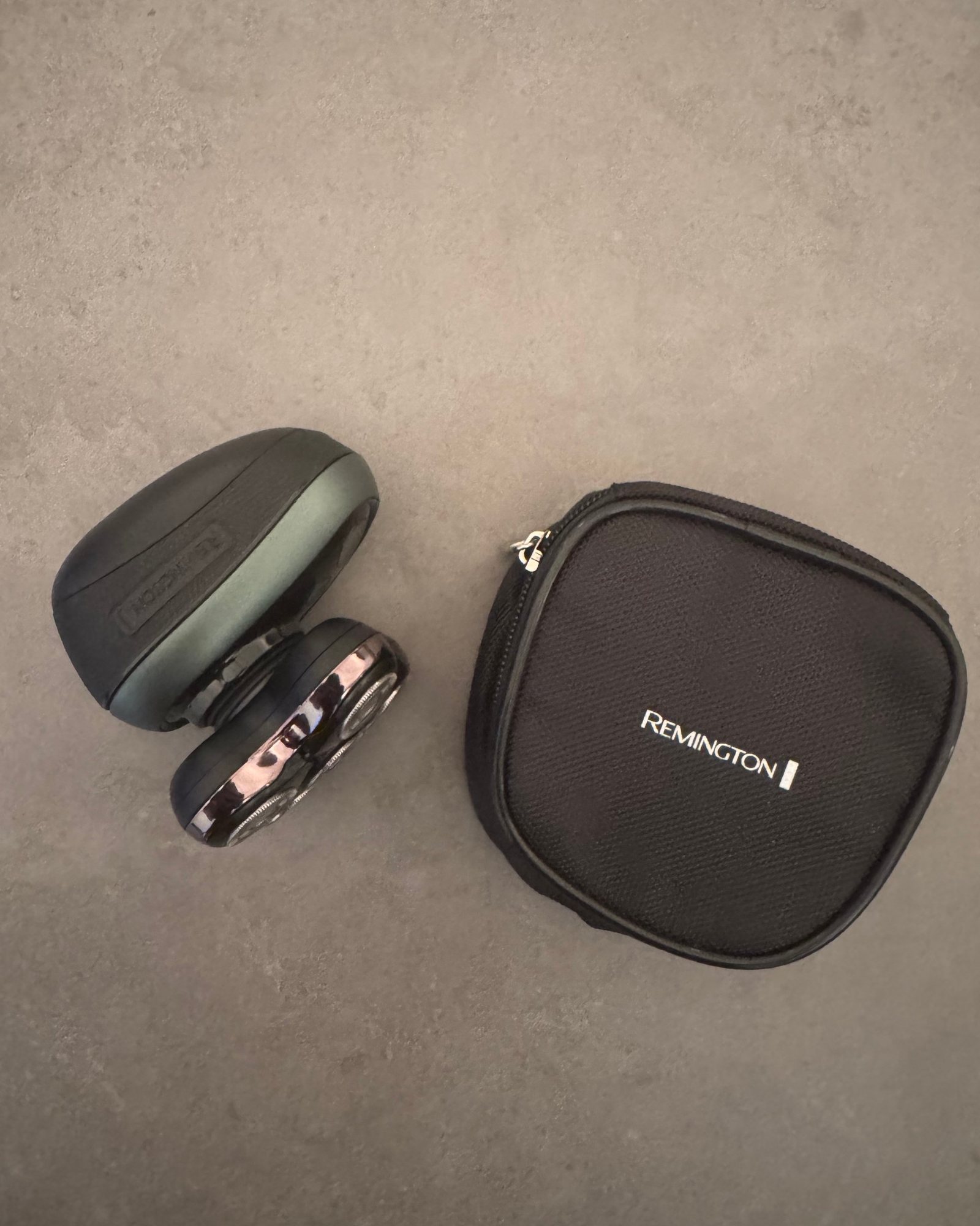 Remington RX7 head shaver beside its zip case on grey concrete